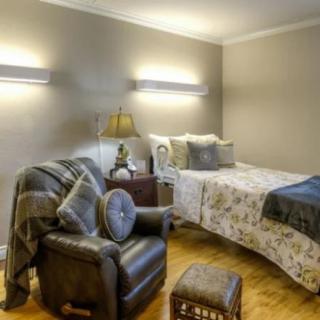 A cozy bedroom with a bed and an armchair, featuring soft lighting and comfortable decor.