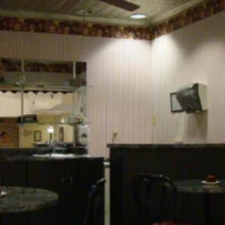 A cozy interior view of a small restaurant featuring tables, chairs, and warm lighting.