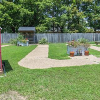 A well-maintained backyard with a grassy lawn, pathways, and planters, surrounded by a wooden fence and trees.