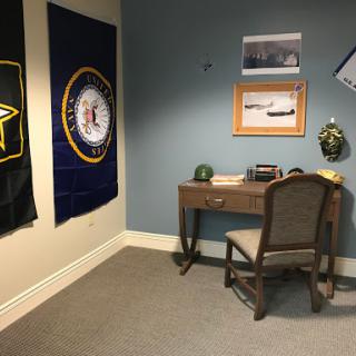 A military-themed office space featuring insignia and a modest desk setup.