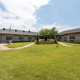 A residential apartment complex with a central courtyard featuring a well-maintained lawn and pathways.