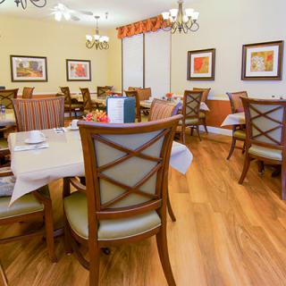 A cozy dining room with neatly arranged tables and chairs, featuring elegant decor and warm lighting.