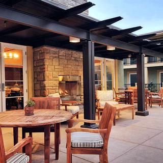 A cozy patio area with wooden furniture and a fireplace under a pergola.