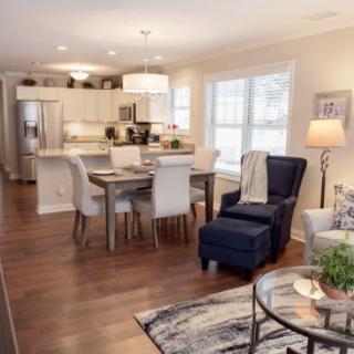 A modern open-concept living space featuring a cozy living room, dining area, and kitchen with hardwood floors.