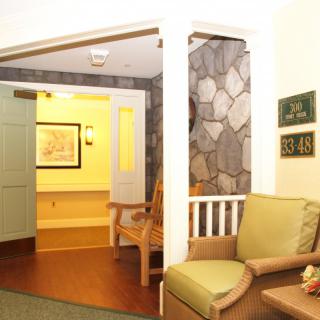 A cozy seating area with armchairs near a doorway, featuring wood flooring and stone wall decor.