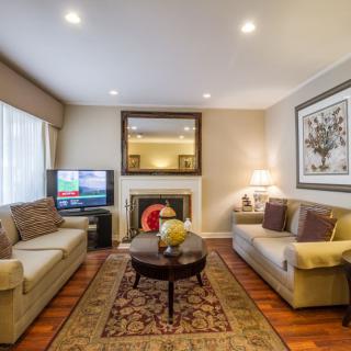 A cozy living room with elegant decor, featuring sofas around a coffee table, a fireplace, and a television.