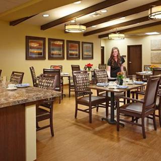 A well-lit dining area with neatly arranged tables and chairs, featuring decorative artwork on the walls.