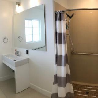 A modern bathroom with a walk-in shower, striped shower curtain, and a sleek sink with a mirror above.