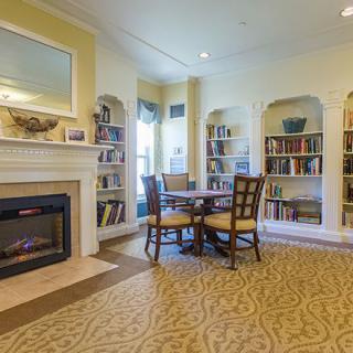 A cozy living room with a fireplace, surrounded by built-in bookshelves and a round table with chairs.