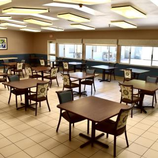 An empty cafeteria with neatly arranged tables and chairs.
