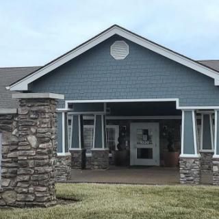 A single-story building with blue siding and stone pillars at the entrance.