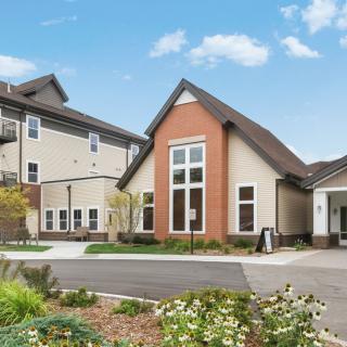 A modern residential building with a landscaped entrance and large windows.