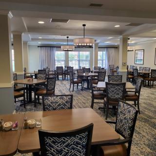 An empty dining room featuring neatly arranged tables and chairs under soft lighting.