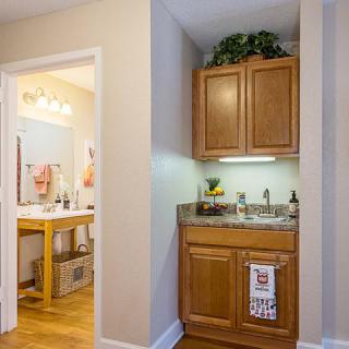 A cozy kitchenette area with wood cabinets adjacent to a bathroom.