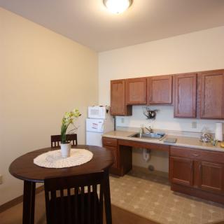 A cozy kitchen with wooden cabinets, a small dining table, and essential appliances.