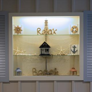 A nautical-themed window display features decorative elements like starfish, seashells, a lighthouse, and the word 'Relax'.