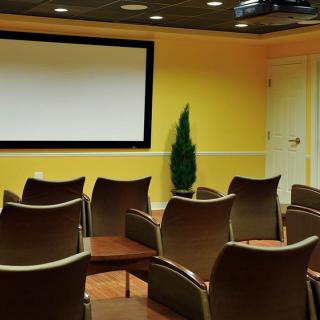 An empty conference room with a projector screen and rows of chairs.