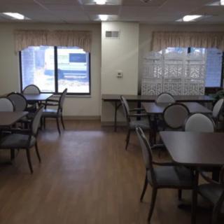 An empty dining area with tables and chairs, featuring a window with curtains.