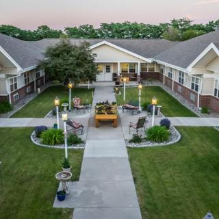 A pleasant courtyard with a pathway leading to a central seating area, flanked by well-maintained lawns and surrounding buildings.