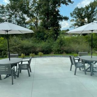 A scenic outdoor patio area with tables and chairs under large umbrellas, surrounded by lush greenery.