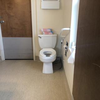 A clean bathroom with a toilet and paper roll holder.