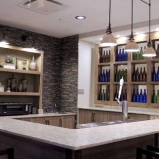 A modern bar interior with a stone wall, illuminated shelves, and a spacious counter.