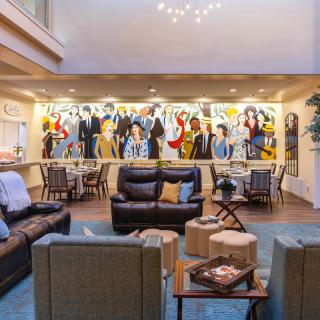 A modern lounge area featuring comfortable seating and vibrant artwork on the walls.
