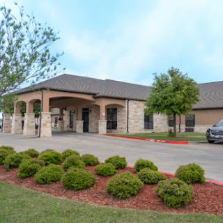 A welcoming exterior view of a commercial building, featuring well-maintained landscaping and parking.