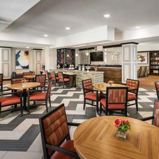 A modern dining area with wooden tables, upholstered chairs, and a stylish chevron-patterned floor.