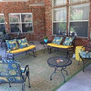 A cozy patio seating area with colorful cushions, metal furniture, and a rug.
