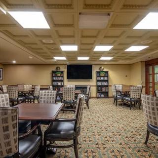 A well-lit dining area featuring multiple tables and chairs, a television, and bookshelves.