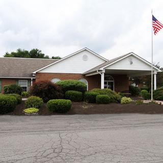 A one-story building with a landscaped front and an American flag next to the entrance.