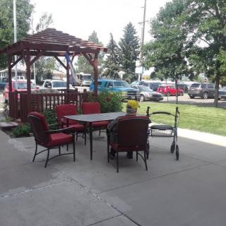 A cozy outdoor patio with a gazebo, featuring a set of chairs and a table on the pavement.