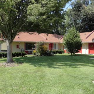 A suburban house with a well-maintained lawn and surrounding trees.