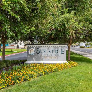 Entrance sign to Solstice Senior Living surrounded by trees and flowers.