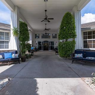 An inviting building entrance adorned with greenery and outdoor seating.