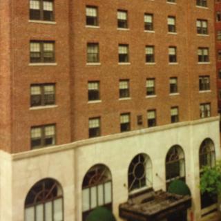 A view of a brick building with multiple windows and arched entrances.