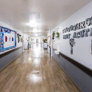 A clean and brightly lit school hallway featuring bulletin boards and signage on the walls.