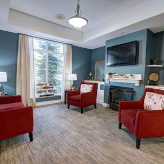 A cozy living room with red chairs, a fireplace, and a TV on blue walls.