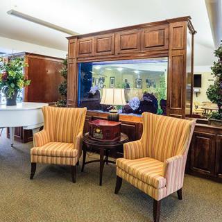 A cozy lounge area with striped armchairs and a grand piano.