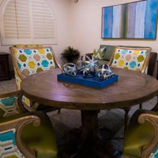 A stylish dining room featuring a round wooden table surrounded by colorful, patterned chairs and a decorative centerpiece.