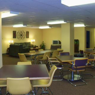 A spacious lounge area with tables, chairs, and sofas under bright lighting.