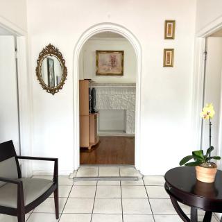 A cozy living room with an archway, mirror, chair, table, and a potted plant.