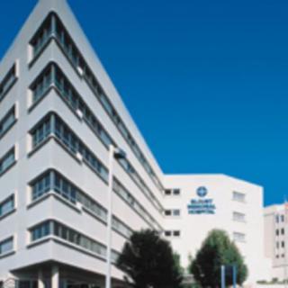 A modern hospital building with distinctive architecture under a clear blue sky.