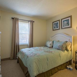 A cozy bedroom with a neatly made bed, decorative pillows, and warmly lit lamp.