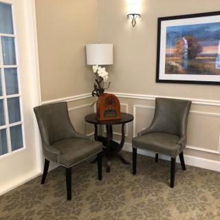 A cozy corner with two chairs, a small table, and a lamp, featuring wall art and elegant decor.