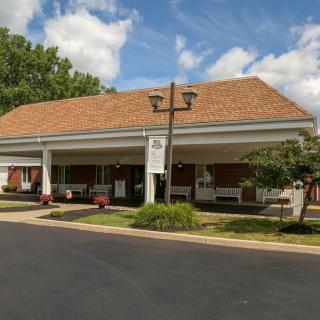 A brick funeral home with an awning and a cloudy blue sky in the background.