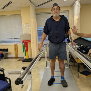 A patient undergoing physical therapy while standing on a walking assistive device.