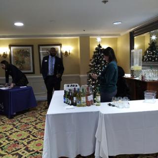 An indoor holiday gathering featuring tables set up with beverages and festive decorations.