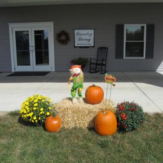 A festive outdoor display with pumpkins, a hay bale, and colorful flowers.